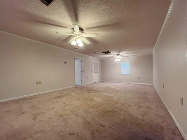 carpeted spare room with a textured ceiling, ceiling fan, and crown molding