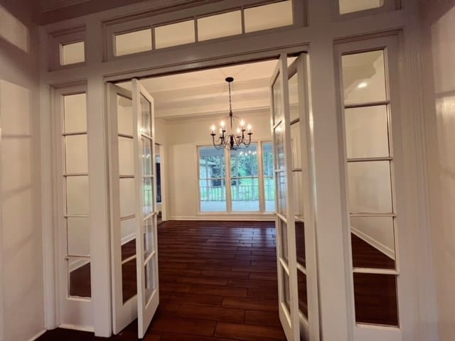 interior space with dark wood-type flooring, a chandelier, and french doors