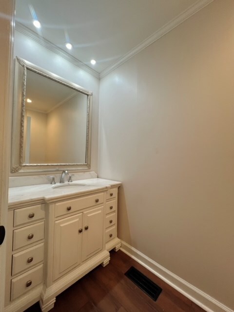 bathroom with hardwood / wood-style floors, vanity, and crown molding