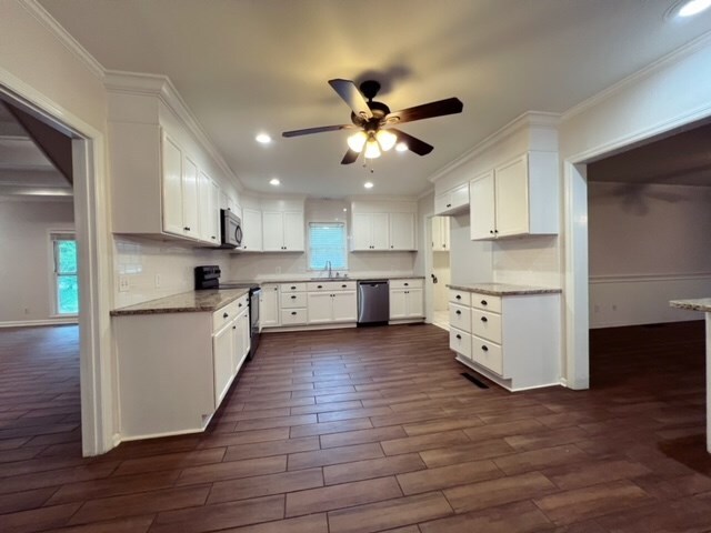 kitchen with white cabinetry, dark hardwood / wood-style flooring, ceiling fan, and stainless steel appliances