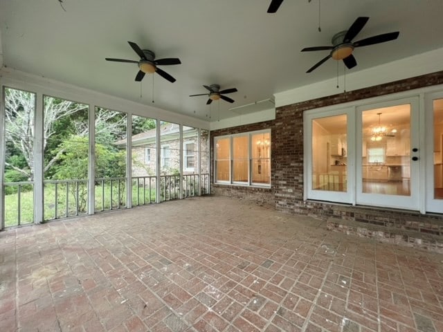 unfurnished sunroom with ceiling fan with notable chandelier