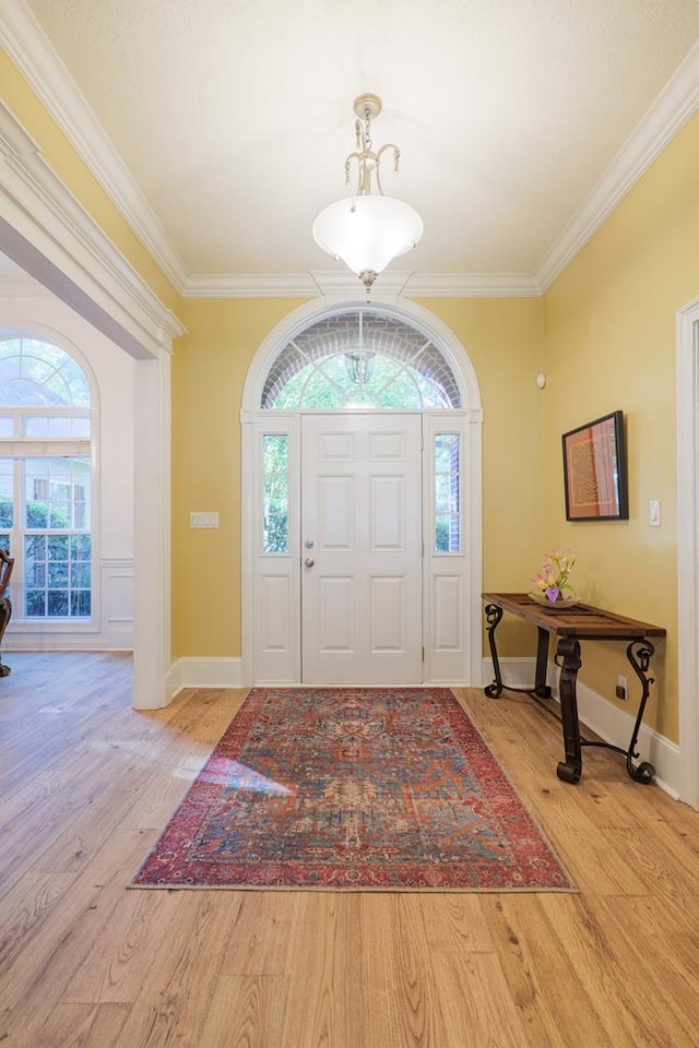 entrance foyer with light wood-type flooring, crown molding, and a wealth of natural light