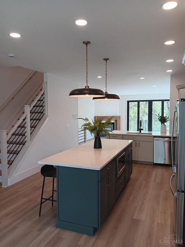 kitchen featuring stainless steel appliances, light wood-style flooring, a kitchen island, light countertops, and recessed lighting