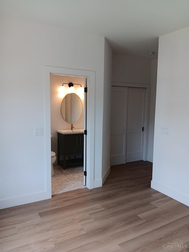 corridor featuring a sink, baseboards, and light wood-style flooring