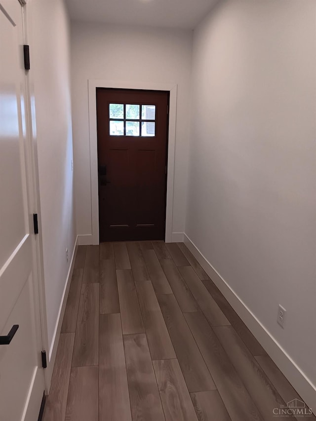 doorway with baseboards and dark wood-type flooring
