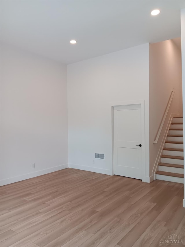 spare room featuring light wood-style flooring, recessed lighting, stairs, and baseboards