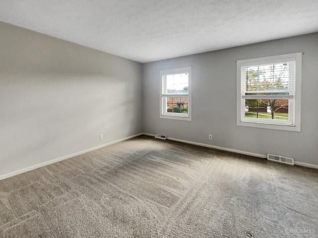 carpeted spare room with a textured ceiling