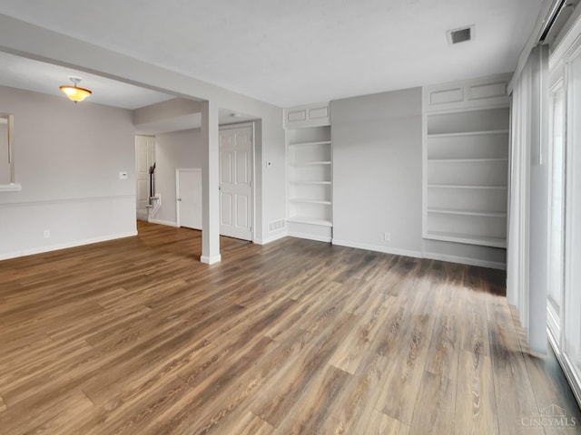 unfurnished living room with dark hardwood / wood-style flooring and built in features