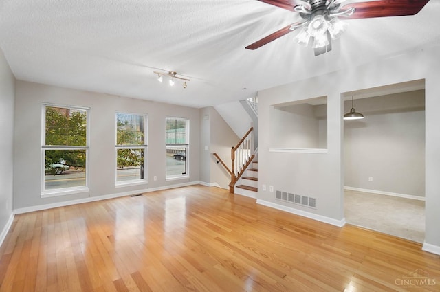 818 William Howard Taft Rd, Cincinnati, OH 45206 - unfurnished living room with light wood-type flooring, stairs, a ceiling fan, and a textured ceiling