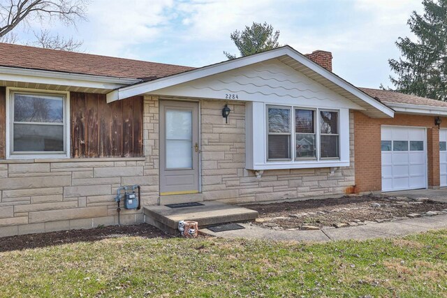 single story home featuring a garage, stone siding, roof with shingles, and a chimney