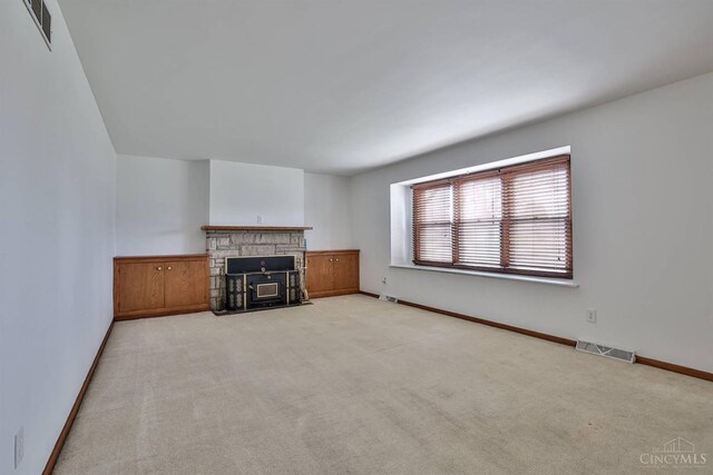 unfurnished living room featuring light carpet, visible vents, and baseboards