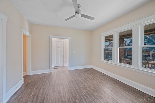 empty room with wood finished floors, baseboards, and ceiling fan