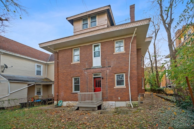 back of house with brick siding, fence, and a chimney