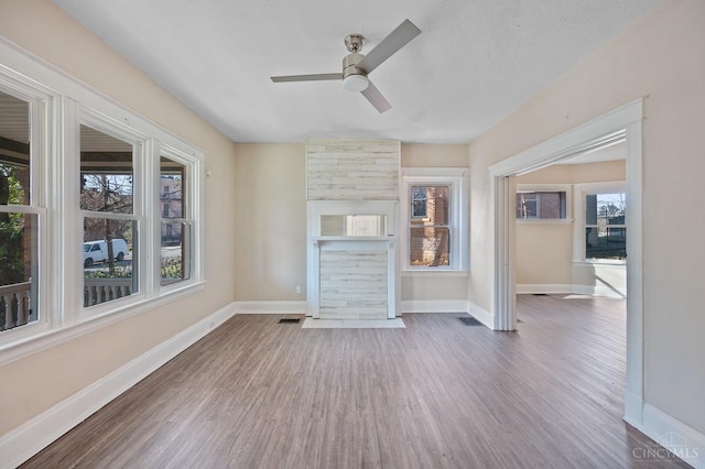 unfurnished living room with wood finished floors, ceiling fan, and baseboards