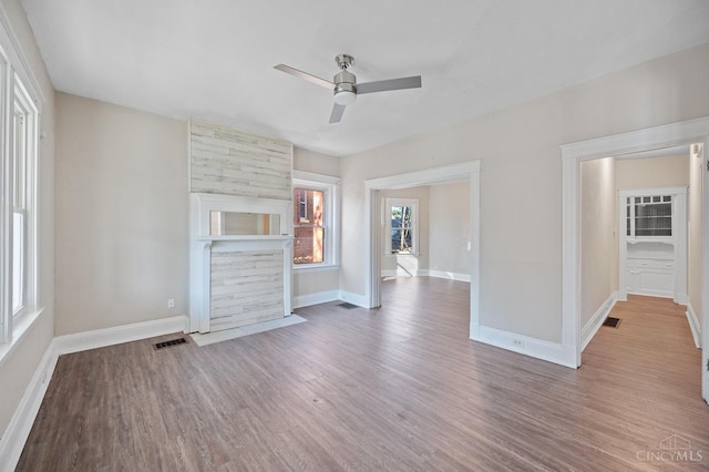 unfurnished living room with a ceiling fan, baseboards, and wood finished floors