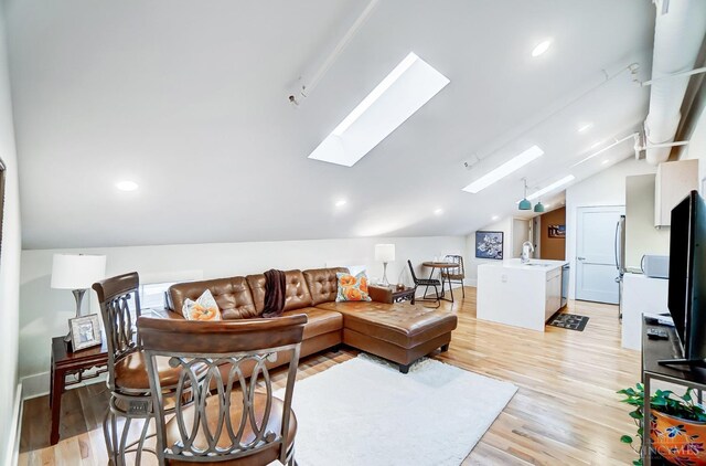 living room with sink, light hardwood / wood-style flooring, and vaulted ceiling with skylight