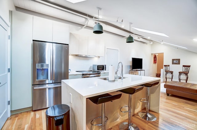 kitchen featuring backsplash, white cabinets, a center island with sink, sink, and stainless steel appliances