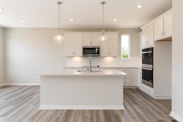 4147 Amelia Olive Branch Rd, Batavia Twp, OH 45103 - kitchen with stainless steel microwave, multiple ovens, light wood-style flooring, tasteful backsplash, and light countertops
