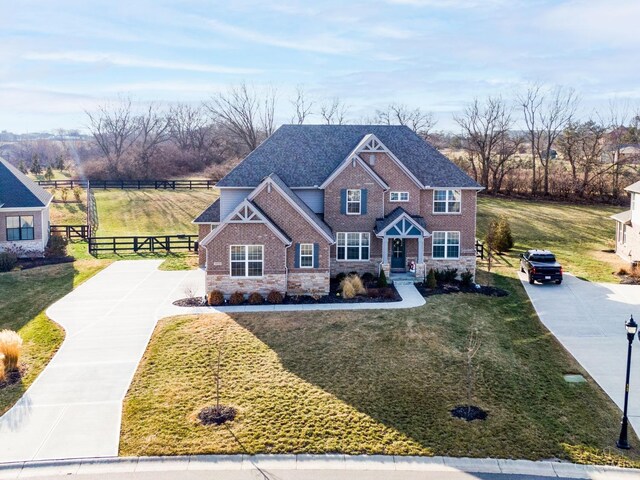view of front of property with a front yard, fence, driveway, stone siding, and brick siding