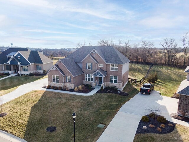 view of front of house with a front yard, stone siding, driveway, and a shingled roof