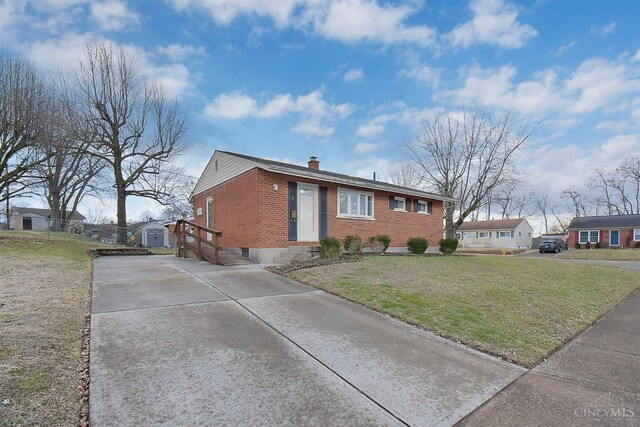 view of front facade featuring brick siding, a chimney, and a front yard