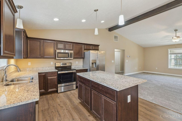 kitchen featuring dark brown cabinetry, appliances with stainless steel finishes, decorative light fixtures, vaulted ceiling with beams, and a sink