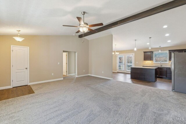 unfurnished living room featuring french doors, vaulted ceiling with beams, carpet flooring, a sink, and baseboards