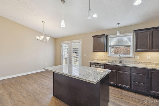 kitchen featuring lofted ceiling, light wood-style flooring, a sink, dark brown cabinets, and dishwasher
