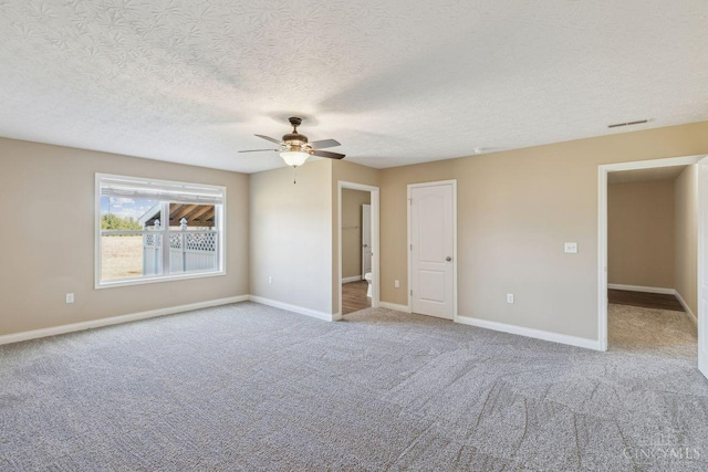 carpeted spare room featuring visible vents, a textured ceiling, baseboards, and a ceiling fan