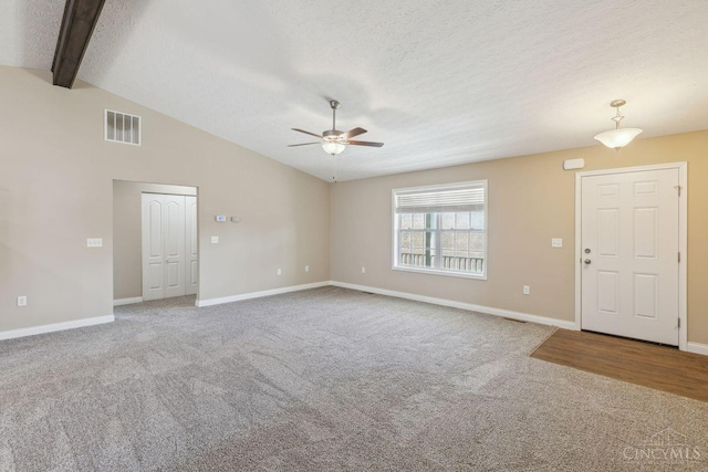 unfurnished living room featuring lofted ceiling with beams, a textured ceiling, carpet flooring, and visible vents