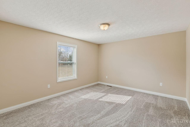 empty room featuring baseboards, a textured ceiling, and light colored carpet