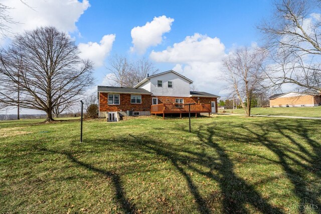 back of property featuring brick siding, a lawn, and a wooden deck