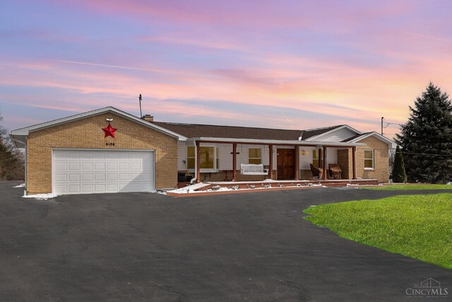 single story home with brick siding, a lawn, driveway, and a garage