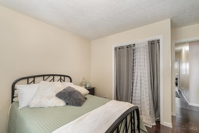 bedroom with dark wood-style floors, baseboards, and a textured ceiling