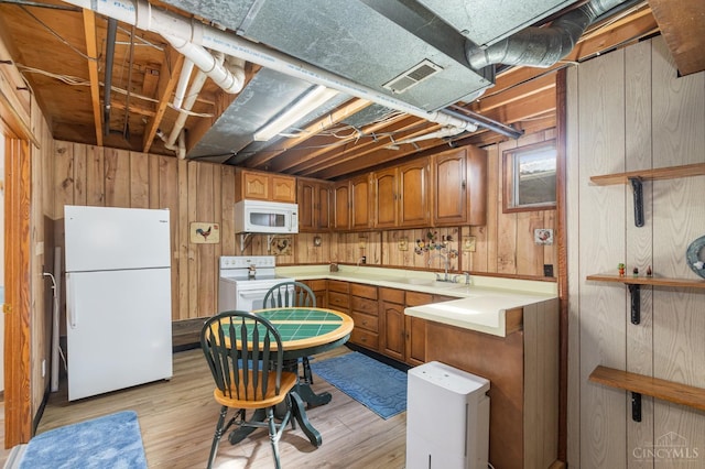kitchen with white appliances, brown cabinetry, wood walls, light wood-type flooring, and a sink
