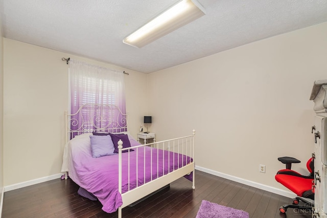bedroom with wood-type flooring, baseboards, and a textured ceiling