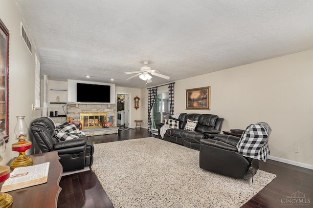 living area featuring a textured ceiling, ceiling fan, a fireplace, baseboards, and wood-type flooring