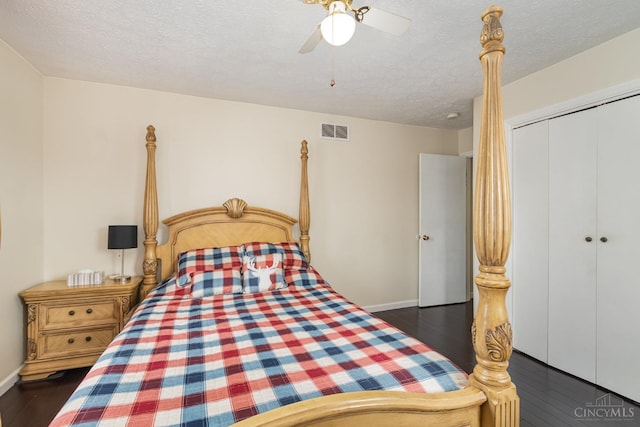 bedroom with dark wood finished floors, a textured ceiling, baseboards, a closet, and a ceiling fan