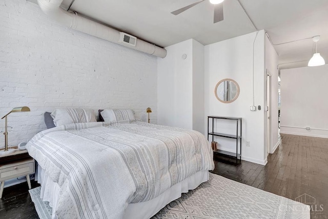 bedroom with visible vents, hardwood / wood-style floors, ceiling fan, brick wall, and baseboards
