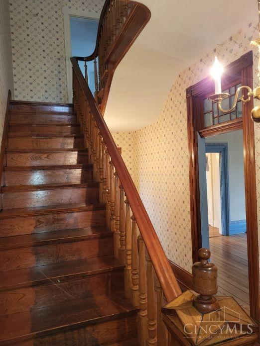 1144 Round Bottom Rd, Union Twp, OH 45150 - staircase featuring wallpapered walls, vaulted ceiling, baseboards, and an inviting chandelier