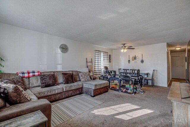 living area with a ceiling fan, carpet, and a textured ceiling