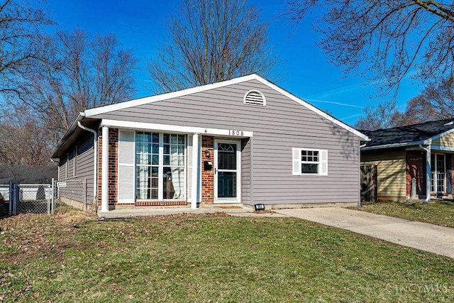 view of front facade with brick siding, a front yard, and fence