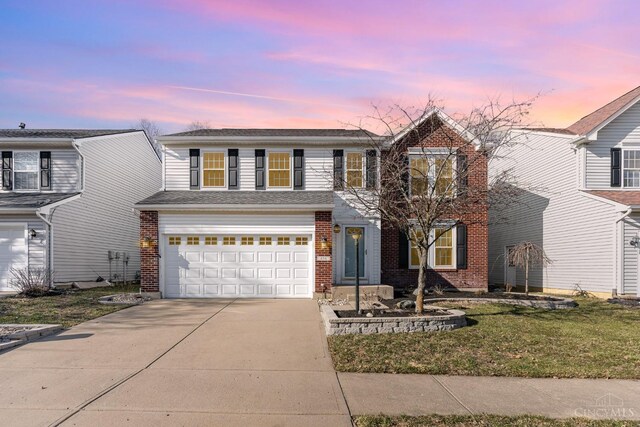 traditional-style home with concrete driveway, an attached garage, brick siding, and a yard