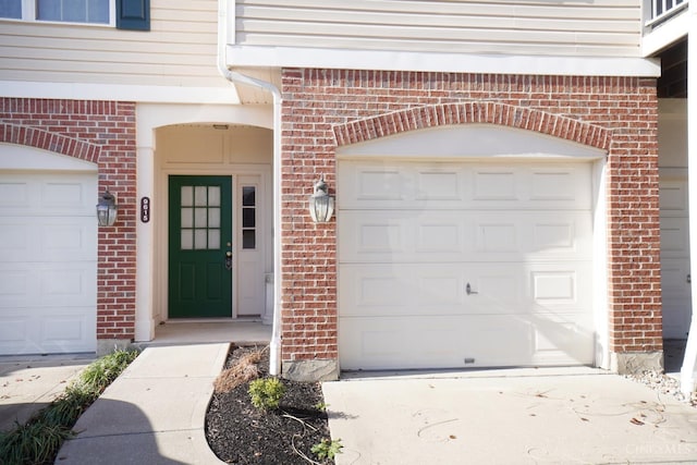 entrance to property with concrete driveway, a garage, and brick siding