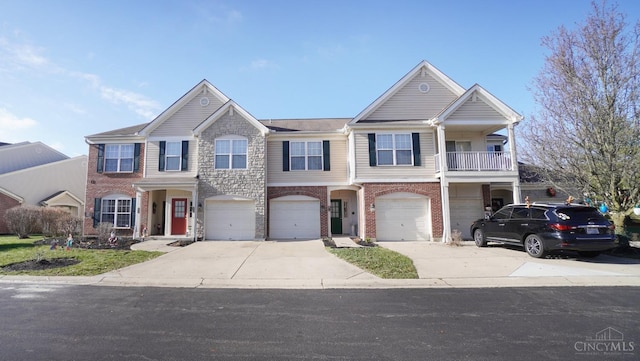 view of property featuring brick siding, an attached garage, a balcony, and driveway