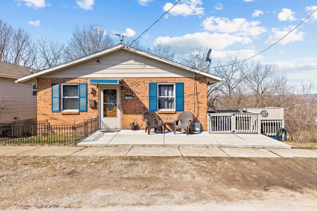 bungalow-style home featuring brick siding and a fenced front yard