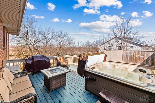 wooden terrace featuring a fire pit, a hot tub, and grilling area