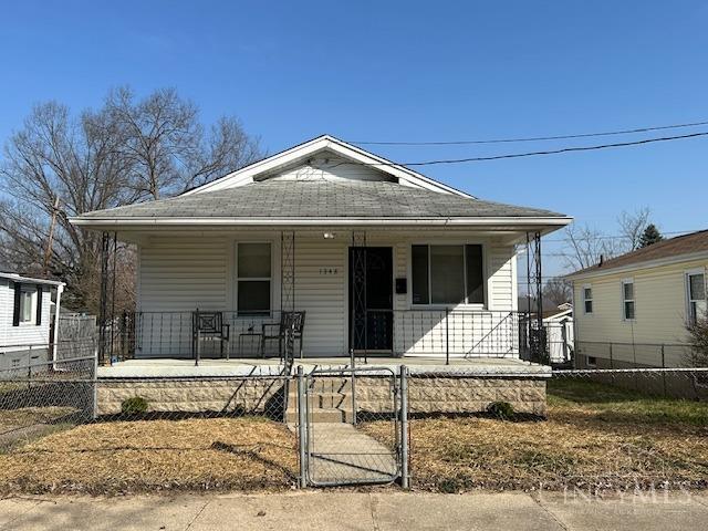 bungalow-style home featuring a fenced front yard, roof with shingles, covered porch, and a gate