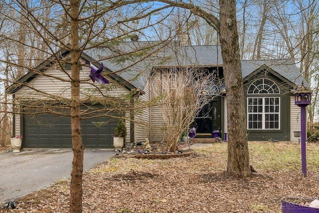 view of front of home featuring a garage, driveway, and roof with shingles