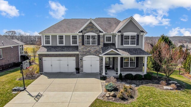 traditional-style home with stone siding, a porch, fence, concrete driveway, and an attached garage